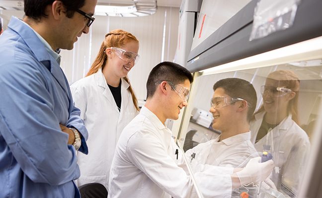 male professor observing male and female students working in lab