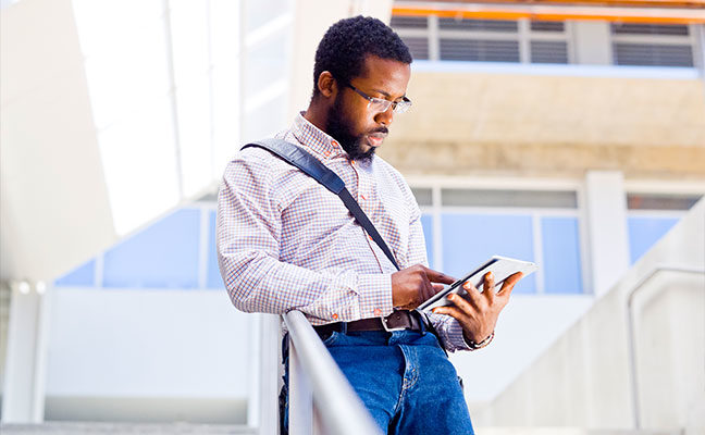 A male student using his tablet device on campus
