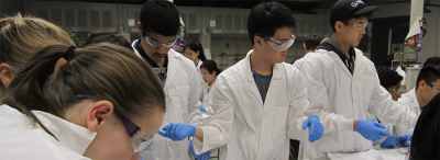 A group of five students in lab coats working on an experiment.