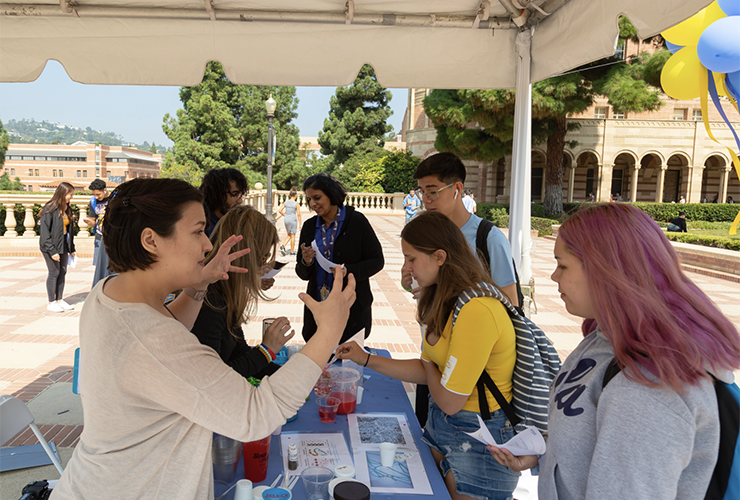 CNSI volunteers talking to students at a public demo booth in Royce quad.