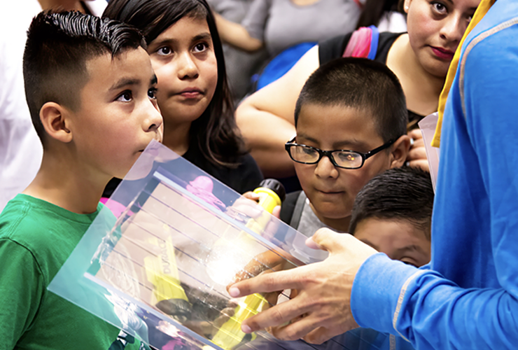 A group of elementary school students are observing the scientific equipment being shown to them.