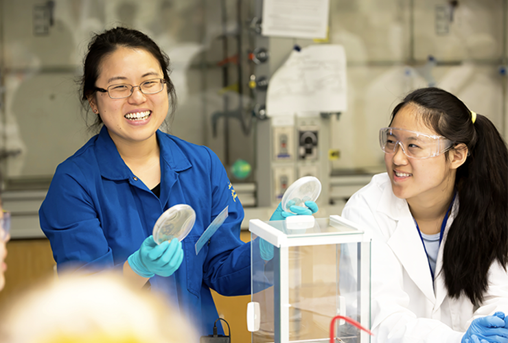 Two smiling volunteers are demonstrating a science experiment.