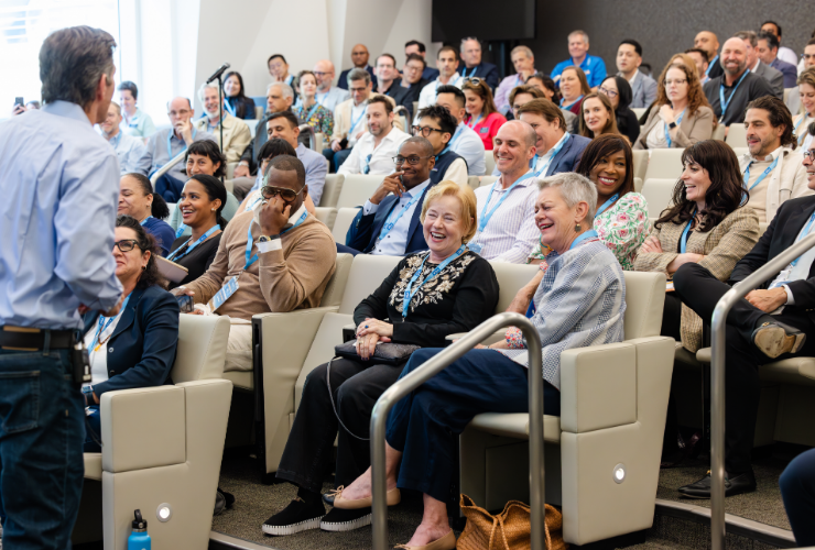 A large, engaged audience of UCLA Anderson alumni laughing and listening to a speaker during an alumni event, reflecting the energy and connection of the Anderson community.