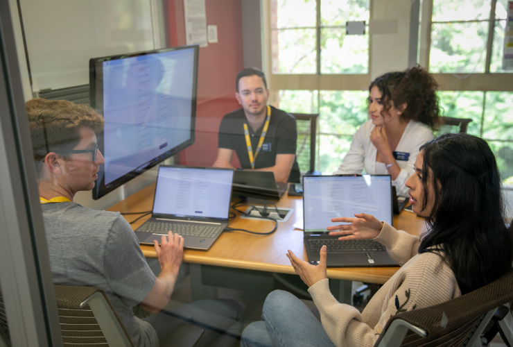 UCLA Anderson students collaborating and brainstorming ideas on a glass wall during an innovative group learning experience.