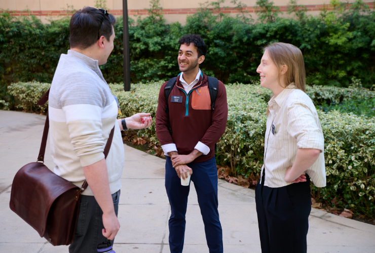 Three UCLA Anderson students smiling and conversing outdoors on campus, reflecting the warmth and community of the Anderson student experience.