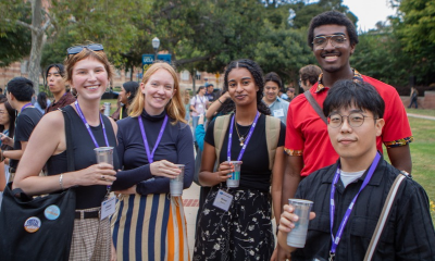 A group of happy students standing in front of some trees.